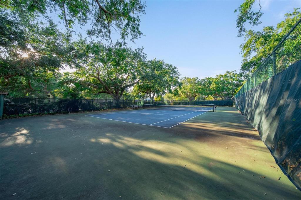An outdoor tennis court is surrounded by a chain-link fence and mature trees — 6033 34TH STREET W UNIT 132, BRADENTON, FL