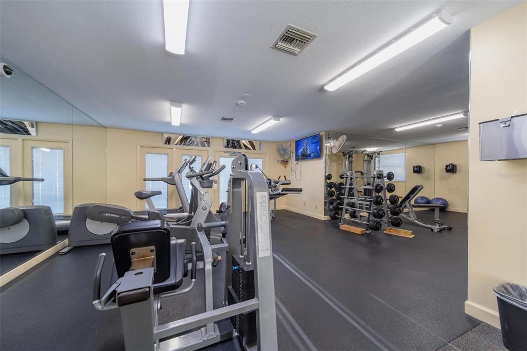 A small fitness center features exercise machines, a weight rack, and mirrored walls — 6033 34TH STREET W UNIT 132, BRADENTON, FL