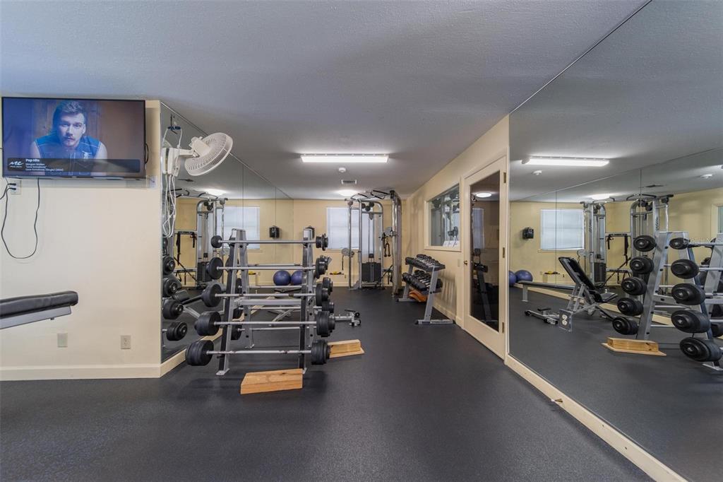A home gym features a weight rack, exercise equipment, mirrored walls, and a television — 6033 34TH STREET W UNIT 132, BRADENTON, FL