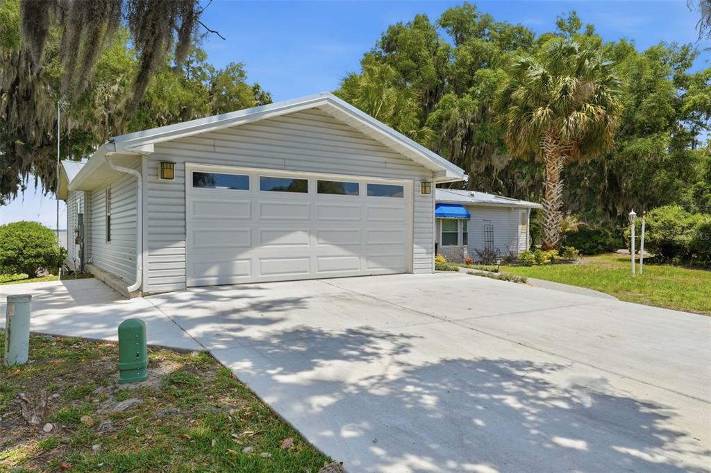 A single-story house with light gray siding, a two-car garage, and blue window awnings — 119 LAKE SHORE CIRCLE, LEESBURG, FL