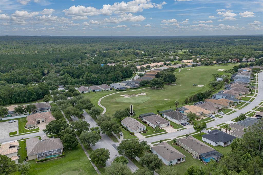 An aerial view shows a residential neighborhood with houses bordering a golf course — 5064 GEVALIA DRIVE, BROOKSVILLE, FL