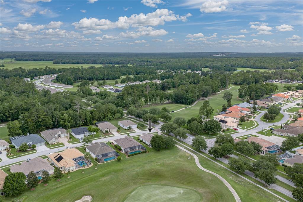 An aerial view shows a residential neighborhood with houses bordering a golf course — 5064 GEVALIA DRIVE, BROOKSVILLE, FL