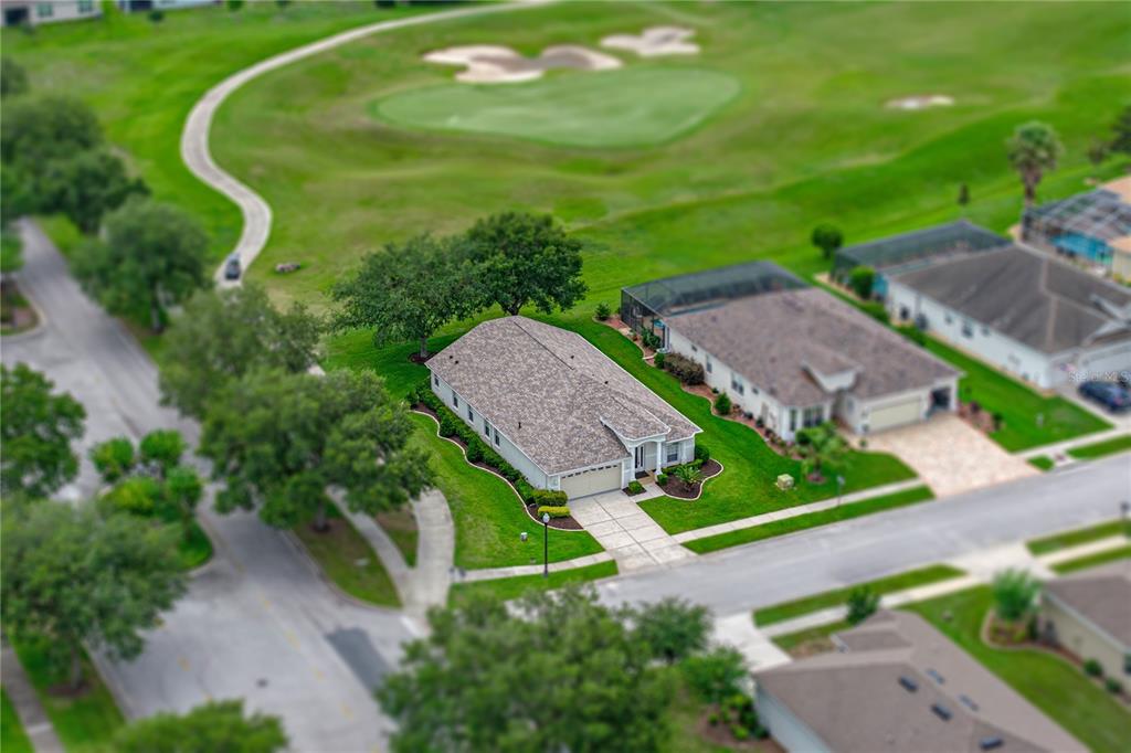 An aerial view shows a single-story house with a shingled roof near a golf course — 5064 GEVALIA DRIVE, BROOKSVILLE, FL