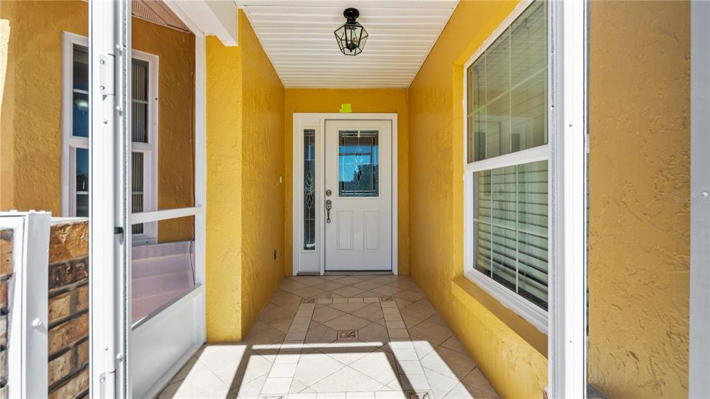 A covered entryway with yellow walls, tiled flooring, and a white front door with glass — 3320 PINERIDGE CIRCLE, KISSIMMEE, FL