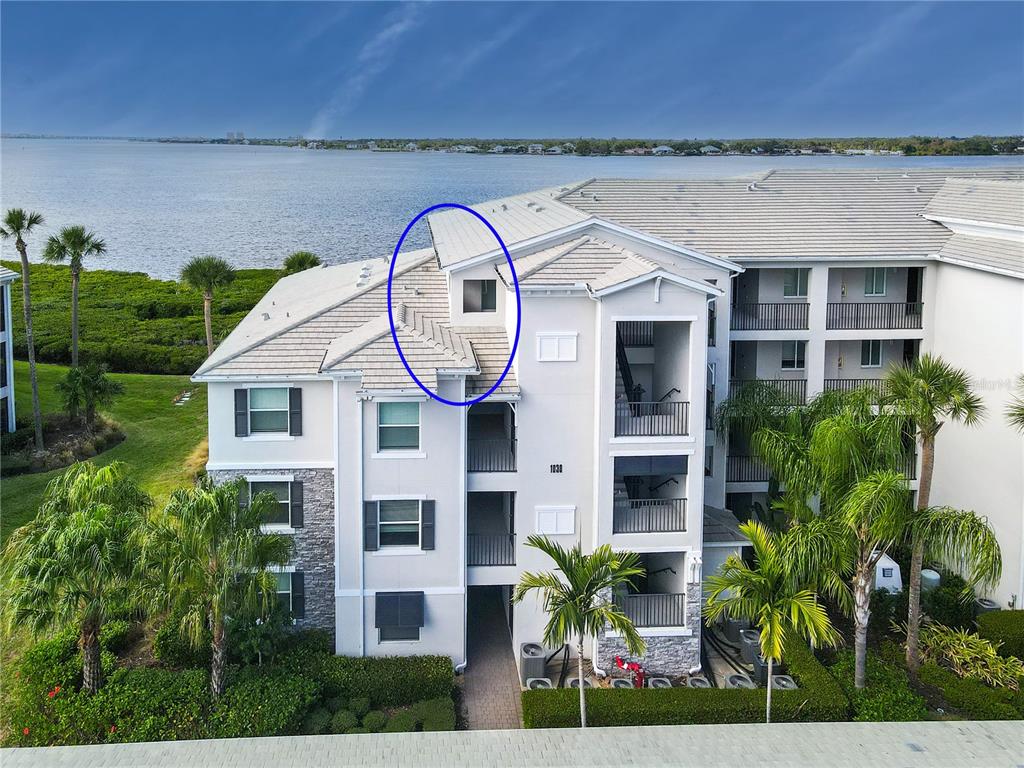 An aerial view shows the exterior of a multi-story apartment building with a circled dormer — 1030 TIDEWATER SHORES LOOP UNIT 401, BRADENTON, FL