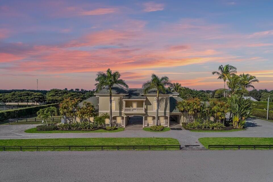 An exterior view of a two-story house with palm trees and a gravel driveway — 4591 South Road, Wellington FL 33414, WELLINGTON, FL