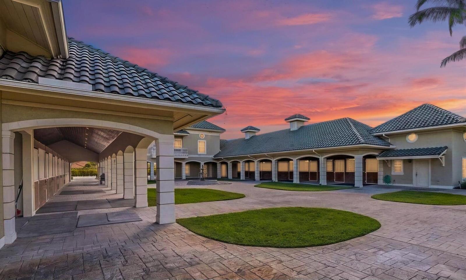 A large, U-shaped equestrian stable building with a paved courtyard and green grass patches — 4591 South Road, Wellington FL 33414, WELLINGTON, FL