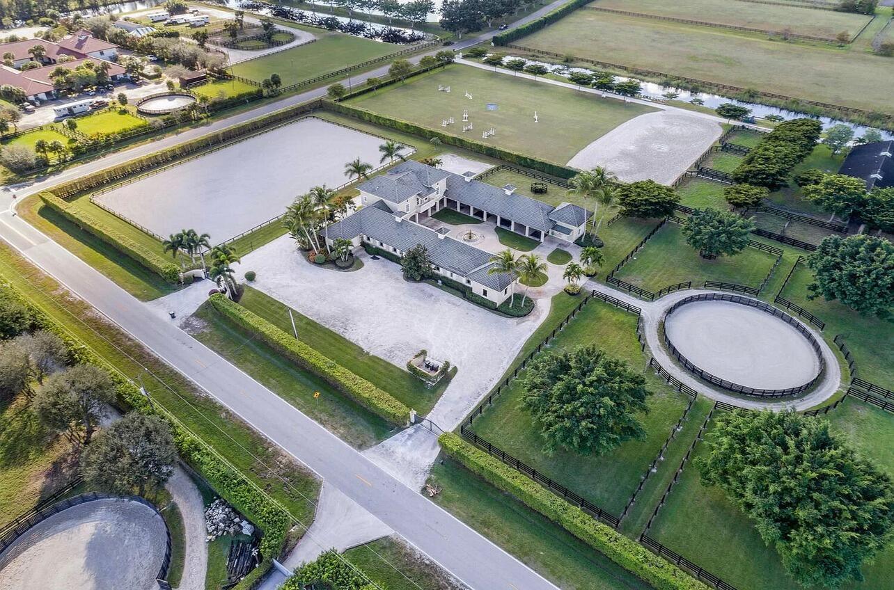 Aerial view of an equestrian estate featuring a central courtyard house, paddocks, and riding arenas — 4591 South Road, Wellington FL 33414, WELLINGTON, FL