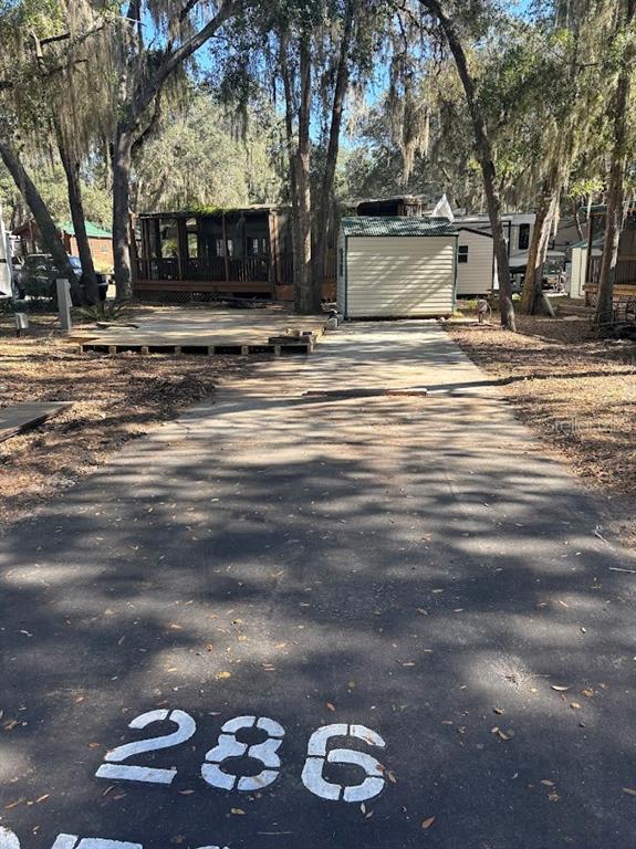 A paved driveway leads to a small shed and a wooden deck in a wooded area — 25287 NE 139TH LANE UNIT 286, SALT SPRINGS, FL