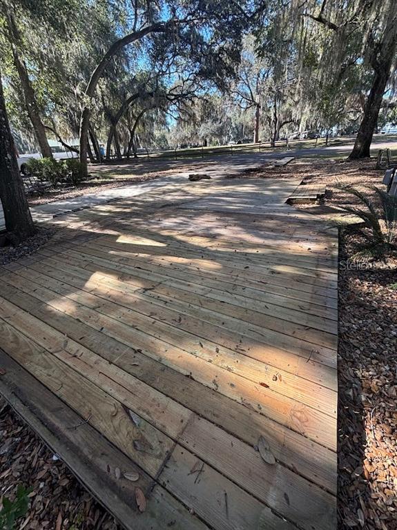 A wooden deck sits under large trees in a wooded outdoor area — 25287 NE 139TH LANE UNIT 286, SALT SPRINGS, FL