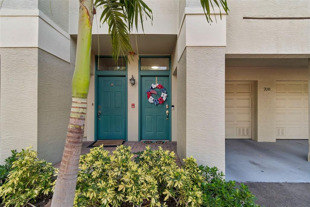 A view of two teal front doors and a garage entrance with a palm tree — 708 SEABOARD PLACE UNIT 708, TAMPA, FL