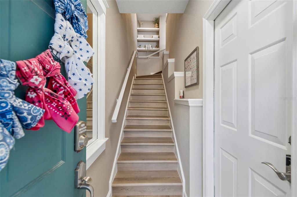 A staircase with wood-look steps leads upward between a teal door and a white door — 708 SEABOARD PLACE UNIT 708, TAMPA, FL