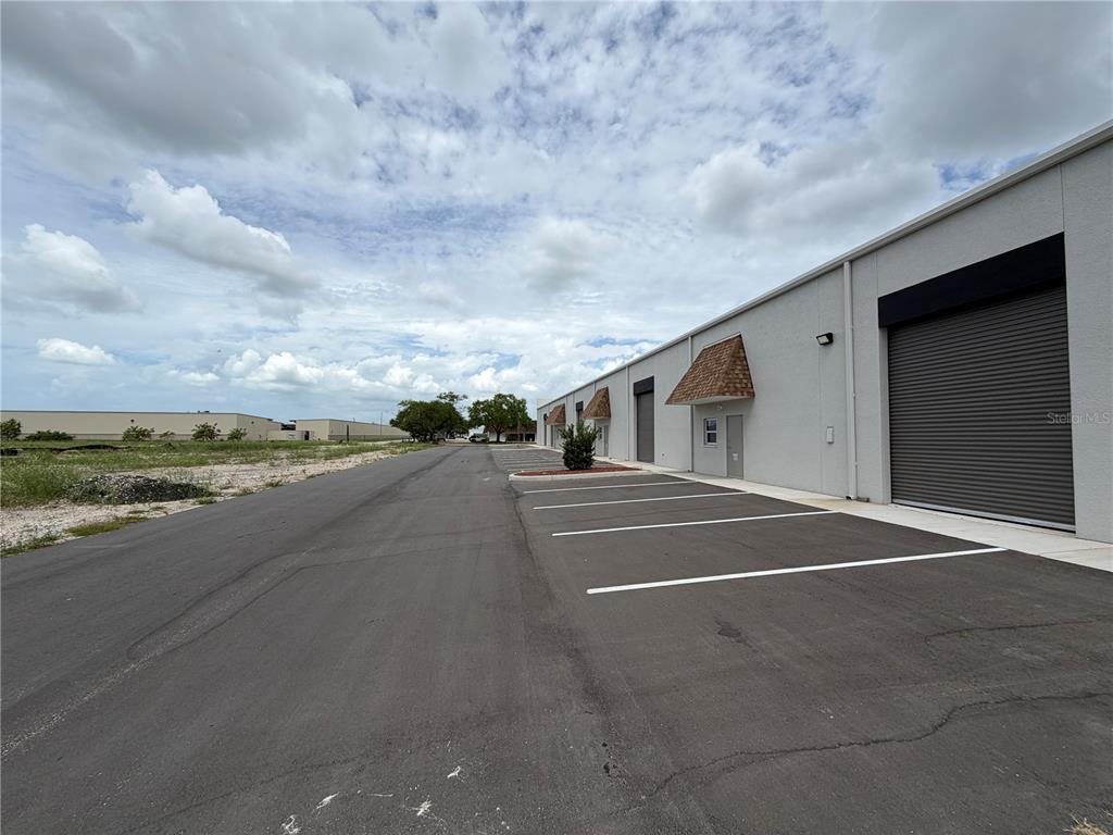 An exterior view of a commercial warehouse building with a paved parking lot — 9224 130TH AVENUE N, LARGO, FL