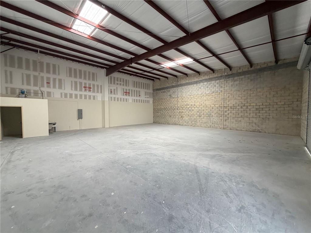An empty warehouse space features a concrete floor, block walls, and exposed ceiling beams — 9224 130TH AVENUE N, LARGO, FL