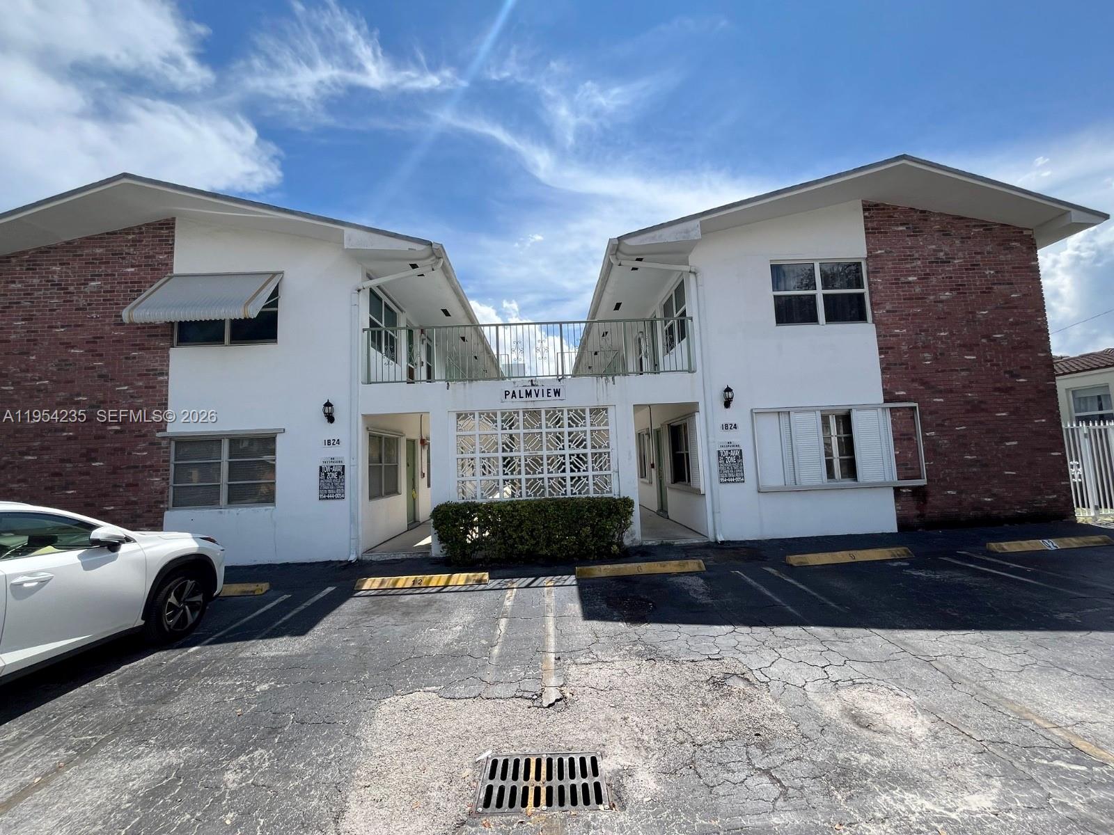 A two-story apartment building with brick accents and a central walkway under a blue sky — 1824 Monroe St # 1, Hollywood FL 33020, HOLLYWOOD, FL