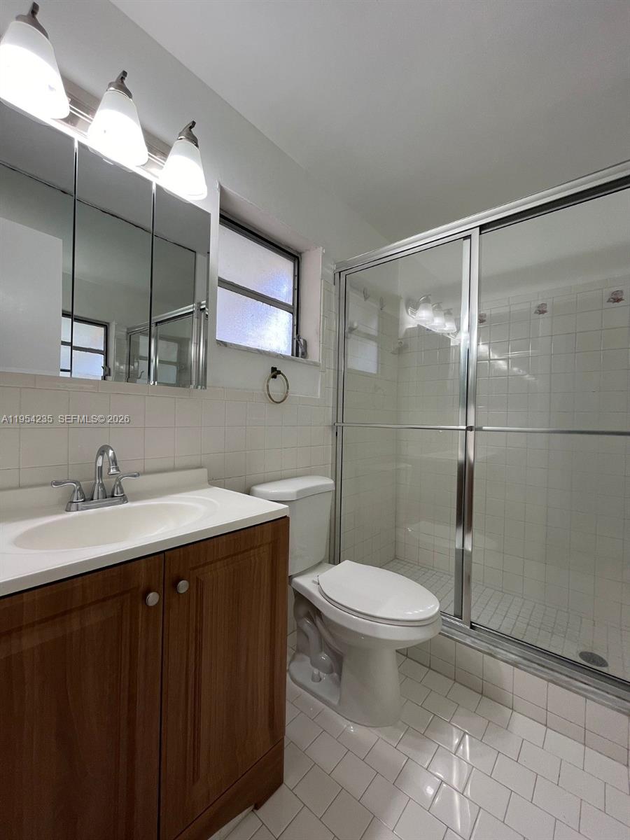 A bathroom features a vanity with a white sink, a toilet, and a glass-enclosed shower — 1824 Monroe St # 1, Hollywood FL 33020, HOLLYWOOD, FL