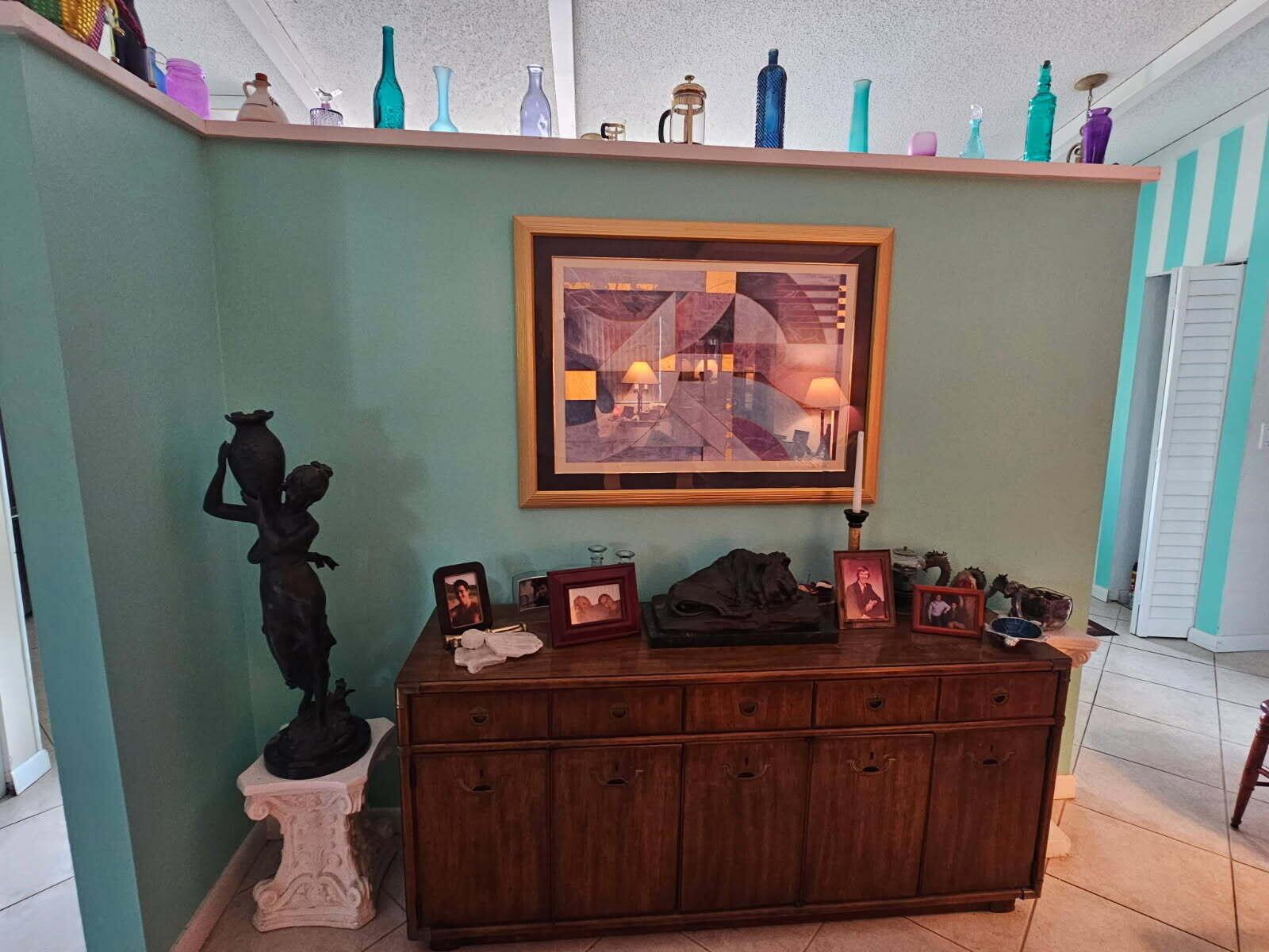 A teal wall features a framed abstract print, a wooden sideboard, and decorative glass bottles — 6551 Winding Brooke Way, Delray Beach FL 33484, DELRAY BEACH, FL