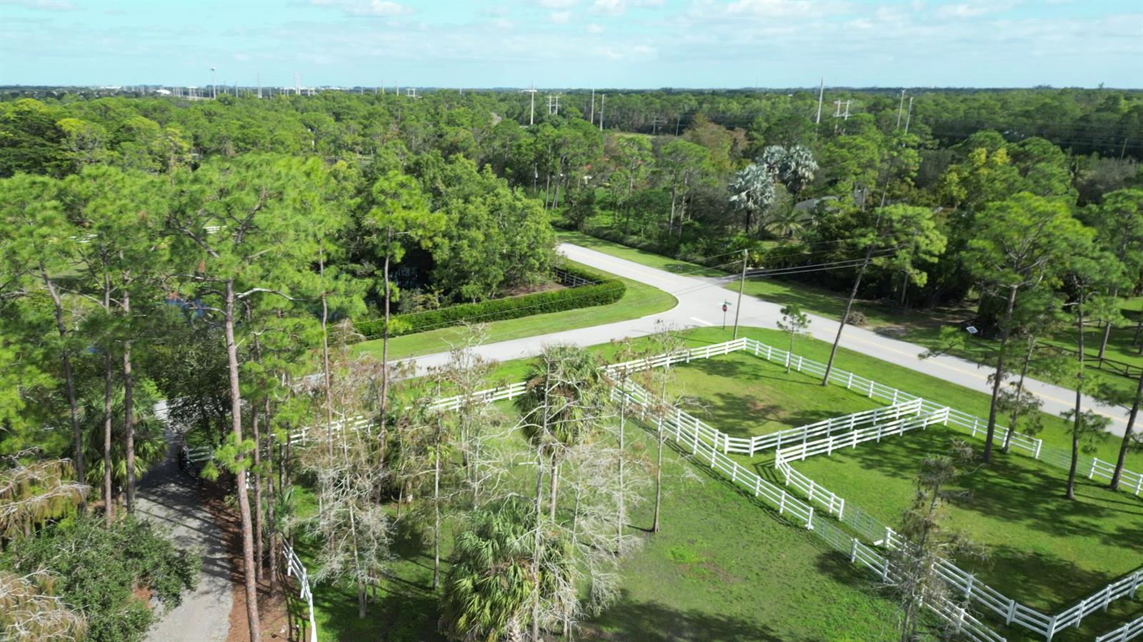 An aerial view shows a fenced grassy pasture, trees, and a paved road — 11176 Ira Lane, Lake Worth FL 33449, LAKE WORTH, FL