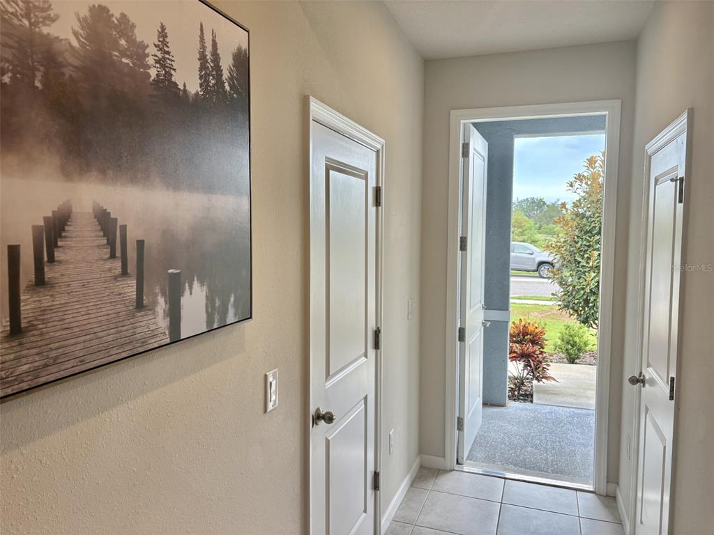 An entryway with tile flooring, two white doors, and a large landscape wall art piece — 4298 HARBOUR PALM DRIVE, HOLIDAY, FL