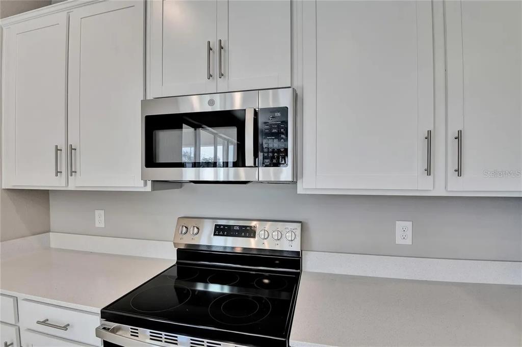 A kitchen features white cabinets, stainless steel appliances, and light-colored countertops — 560 SUMMIT RIVER DRIVE, APOPKA, FL