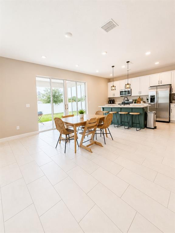 A kitchen and dining area feature white cabinets, a green island, and light tile flooring — 560 SUMMIT RIVER DRIVE, APOPKA, FL