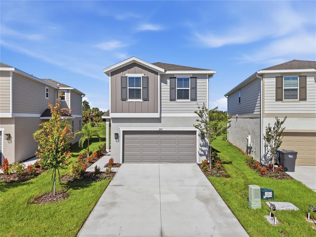 A two-story suburban house features a gray garage, light siding, and a concrete driveway — 2427 29TH LANE E, PALMETTO, FL
