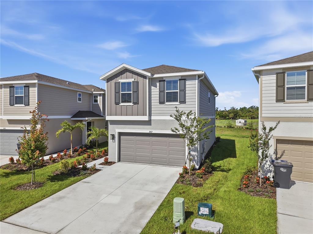 A two-story suburban house with a gray garage and light-colored siding under a blue sky — 2427 29TH LANE E, PALMETTO, FL