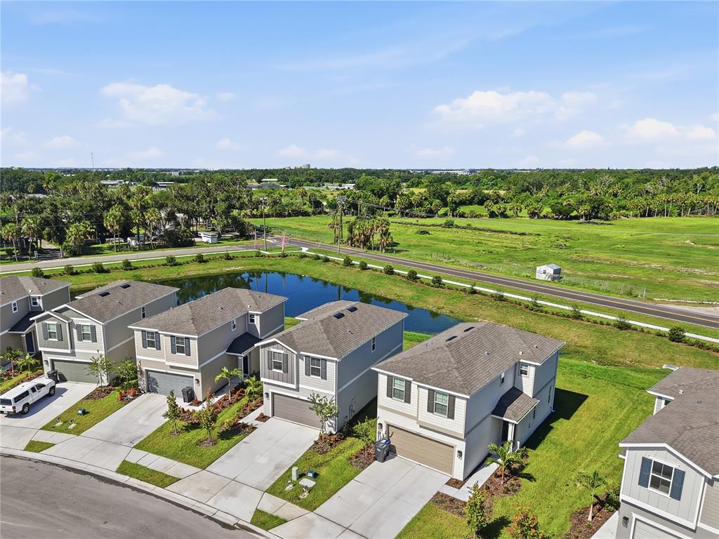 An aerial view shows several suburban houses with driveways situated next to a retention pond — 2427 29TH LANE E, PALMETTO, FL