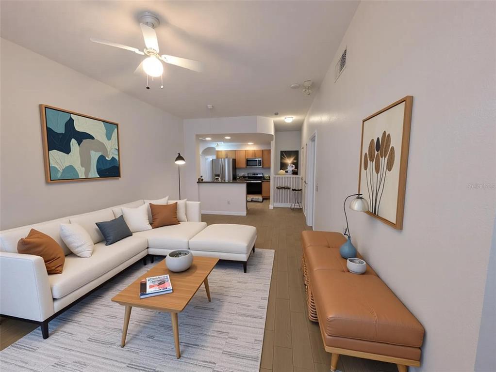 A living room with a white sectional sofa, coffee table, and an open kitchen beyond — 4015 VENETIAN BAY DRIVE UNIT # 103, KISSIMMEE, FL