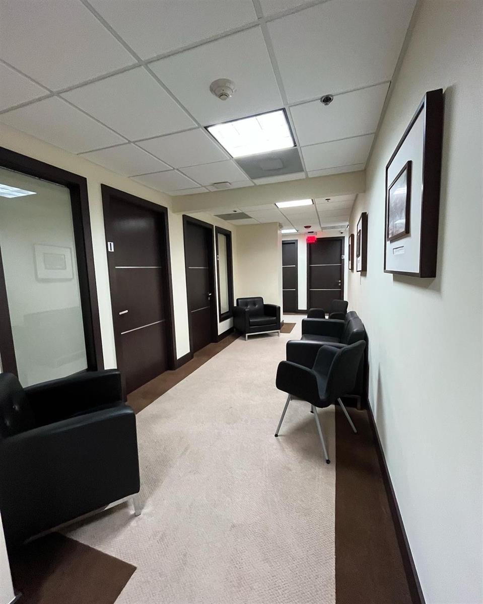 A narrow office hallway features dark wood doors, black armchairs, and framed wall art — 2730 SW 3rd Avenue # 202m, Miami FL 33129, MIAMI, FL