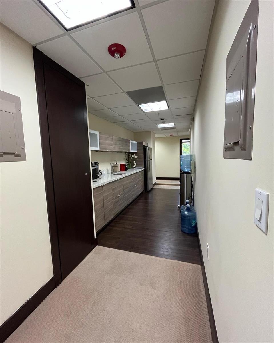 A narrow office kitchenette features wood-look cabinetry, a white countertop, and dark flooring — 2730 SW 3rd Avenue # 202m, Miami FL 33129, MIAMI, FL