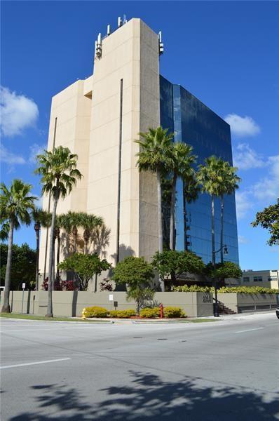 A tall office building with a tan facade and blue glass windows stands behind palm trees — 2730 SW 3rd Avenue # 202m, Miami FL 33129, MIAMI, FL