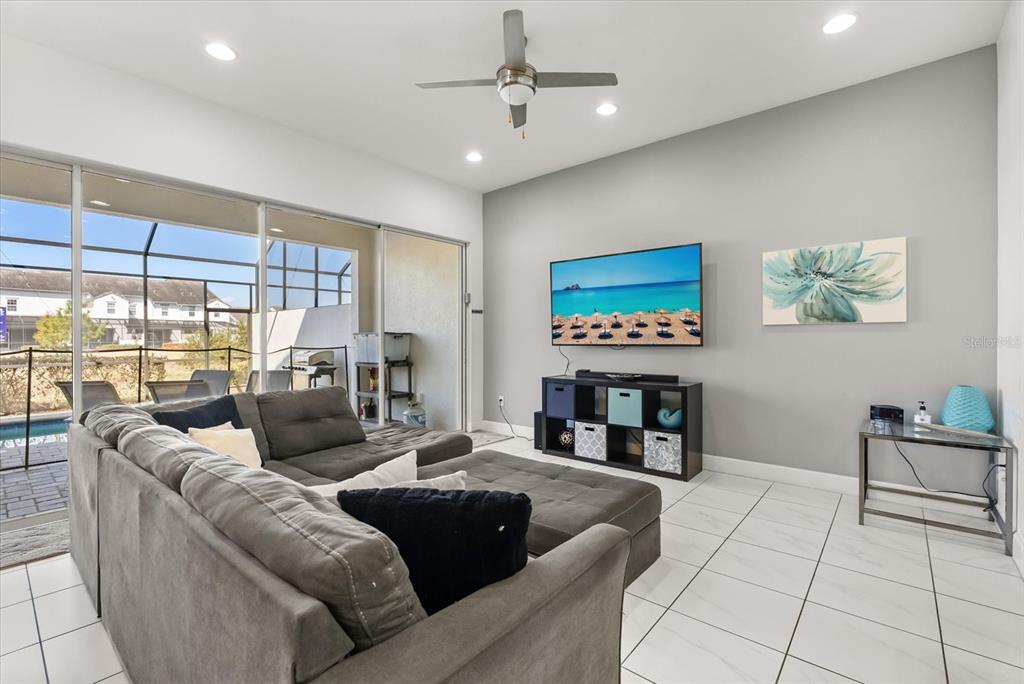 A living room features a grey sectional sofa, a wall-mounted television, and large sliding glass doors — 337 CAPTIVA DRIVE, DAVENPORT, FL