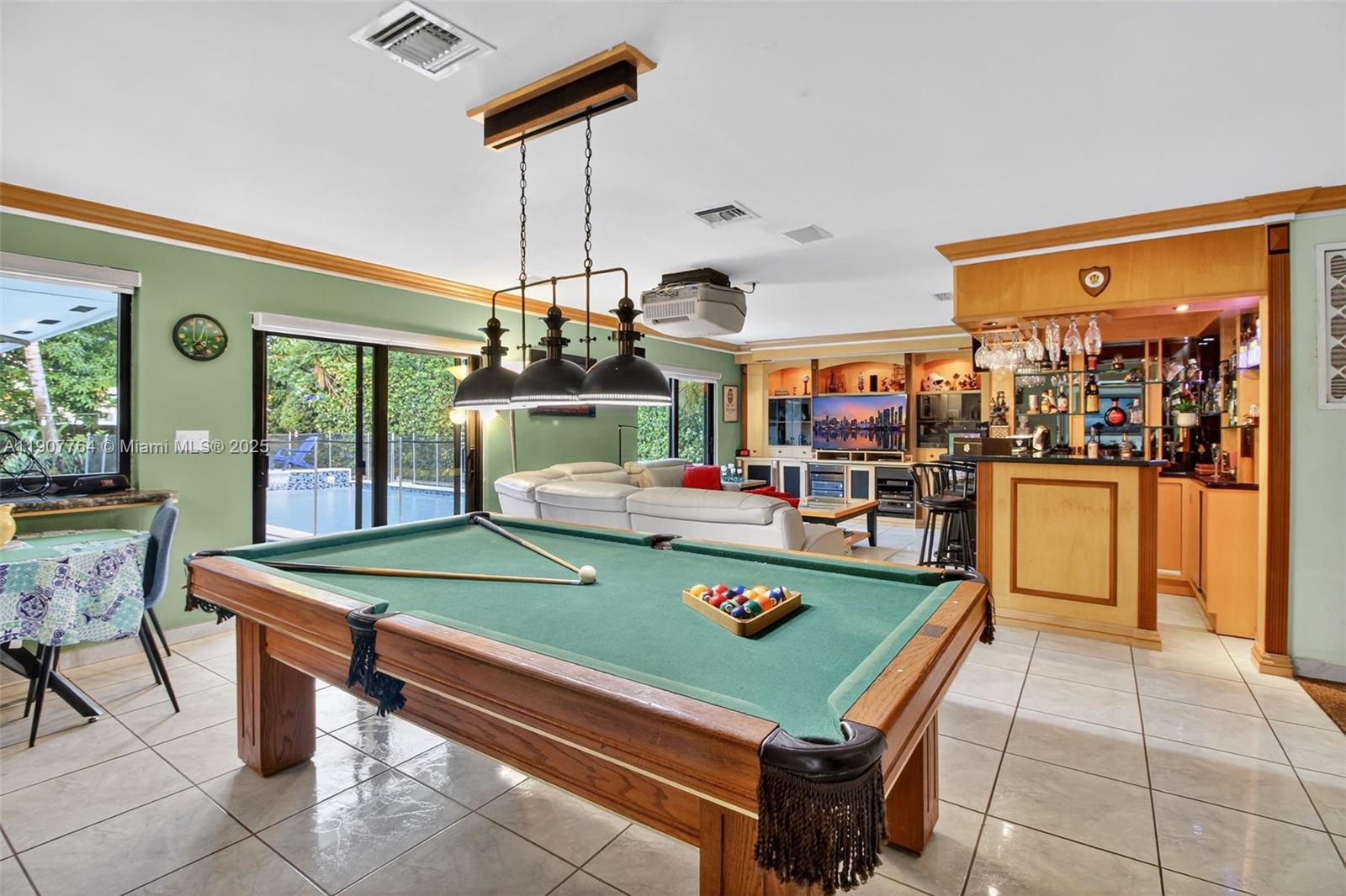 A game room features a pool table, a built-in bar, and a view of a pool — 15010 Dunbarton Pl, Miami Lakes FL 33016, MIAMI LAKES, FL