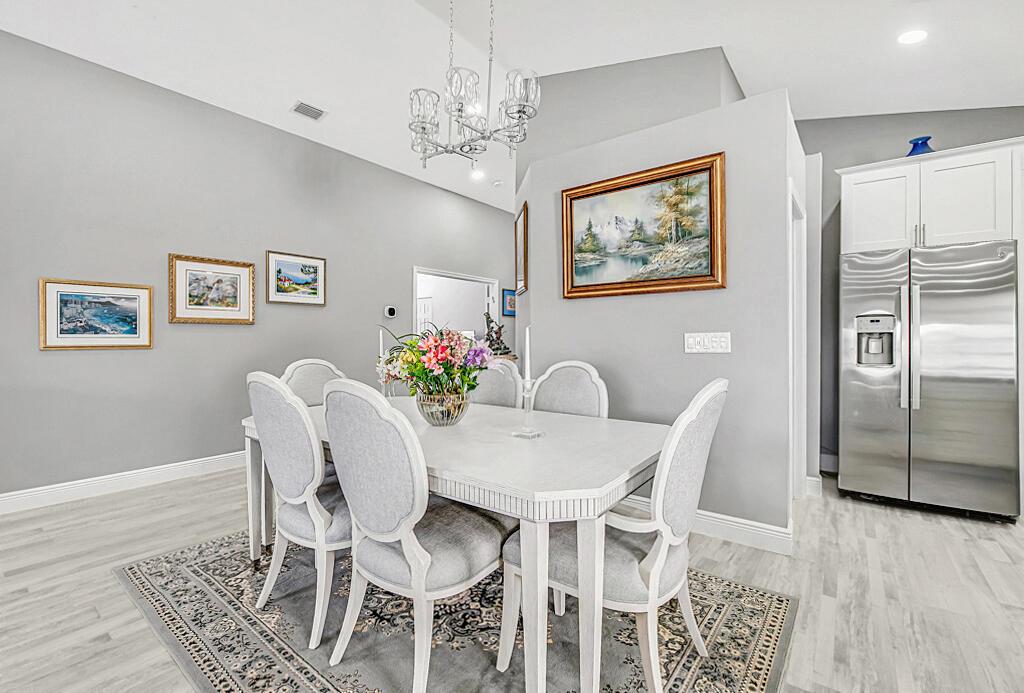 A dining room features a white table, six upholstered chairs, and a crystal chandelier — 8075 Duomo Circle, Boynton Beach FL 33472, BOYNTON BEACH, FL