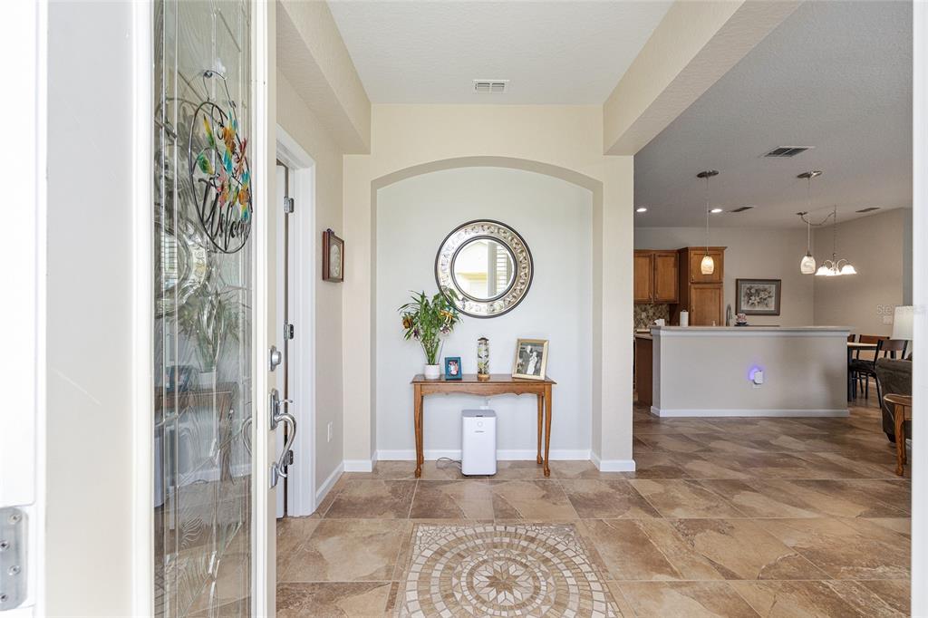 A tiled entryway features an arched wall niche with a console table and round mirror — 7150 SW 91ST COURT, OCALA, FL
