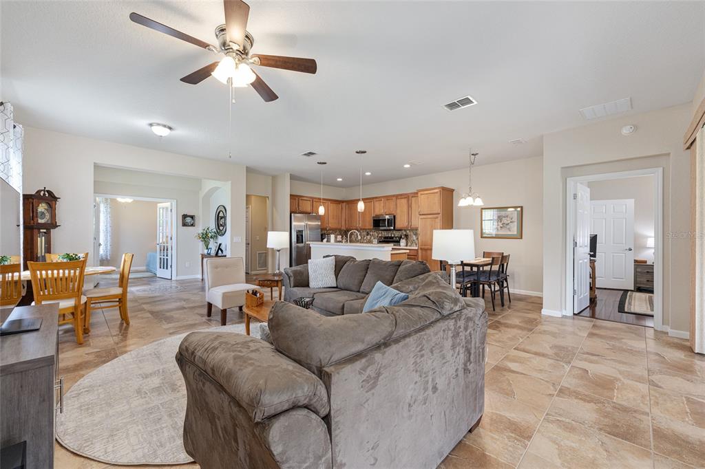 An open-concept living room and kitchen feature tile flooring, a ceiling fan, and neutral walls — 7150 SW 91ST COURT, OCALA, FL
