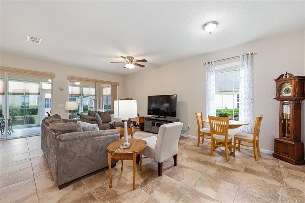 A living and dining area with tile floors, a ceiling fan, and a grandfather clock — 7150 SW 91ST COURT, OCALA, FL
