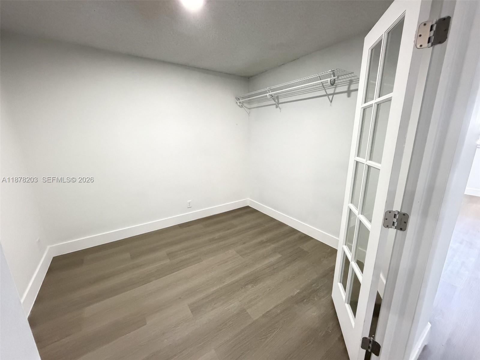 A small, empty closet features white walls, wood-look flooring, and a wire shelving unit — 22605 SW 66th Ave # 403, Boca Raton FL 33428, BOCA RATON, FL
