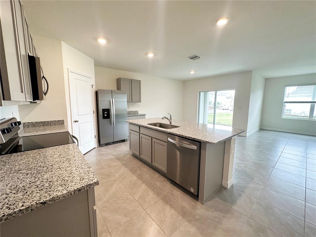 A kitchen with gray cabinets, granite countertops, stainless steel appliances, and an island with sink — 5105 VECCHIO COURT, BRADENTON, FL