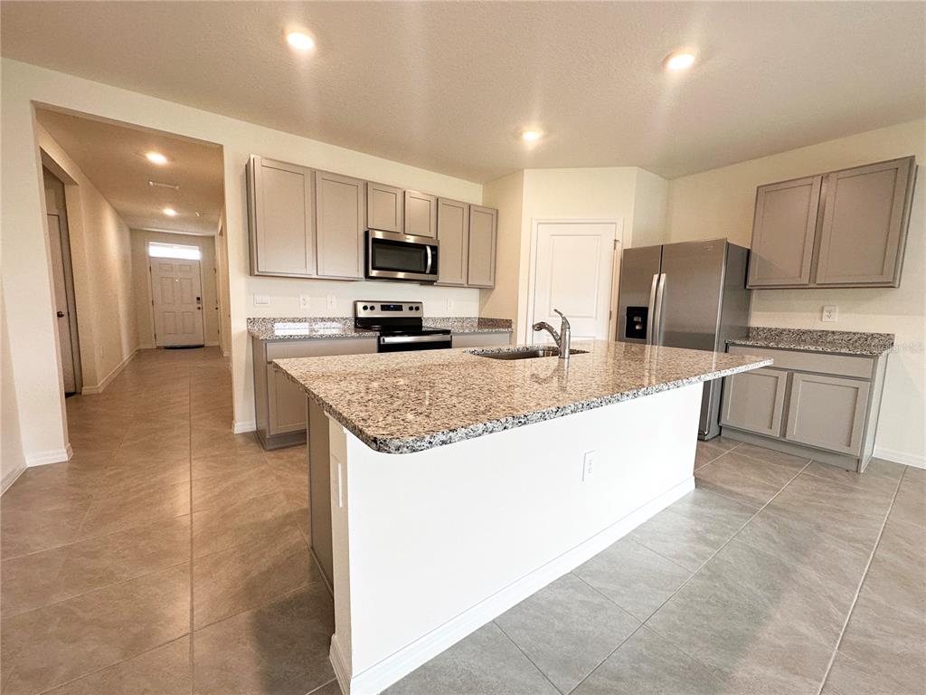 A kitchen features a granite-topped island, stainless steel appliances, and light gray cabinetry — 5105 VECCHIO COURT, BRADENTON, FL