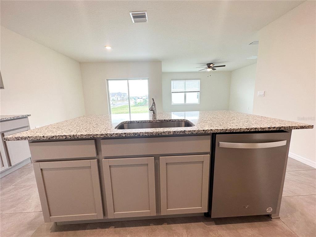 A kitchen island with a granite countertop, stainless steel sink, and dishwasher sits in a room — 5105 VECCHIO COURT, BRADENTON, FL