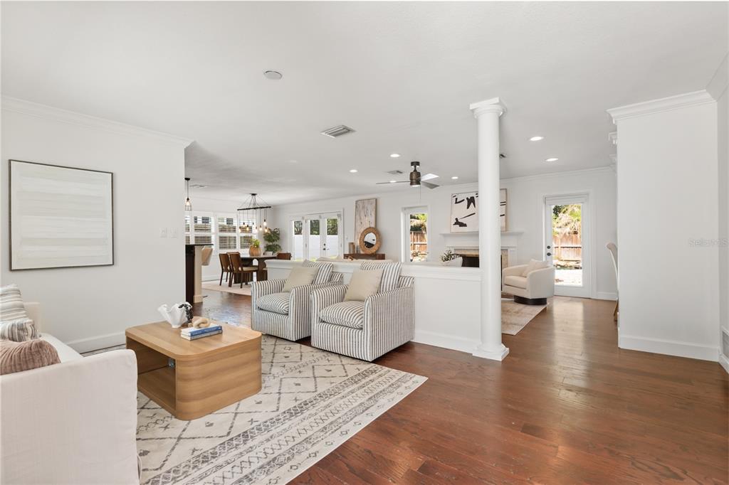 A bright living room features hardwood floors, a half-wall divider, and two striped armchairs — 703 NICOMA TRAIL, MAITLAND, FL