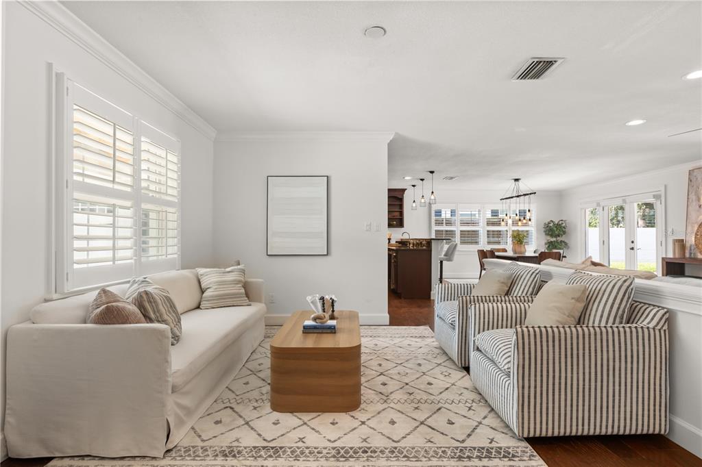 A living room features a white sofa, striped armchairs, a wooden coffee table, and shutters — 703 NICOMA TRAIL, MAITLAND, FL