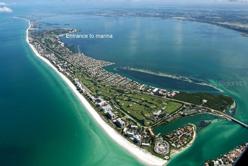 An aerial view shows a coastal barrier island with a beach, golf course, and residential buildings — 2600 HARBOURSIDE DRIVE UNIT O-04, LONGBOAT KEY, FL