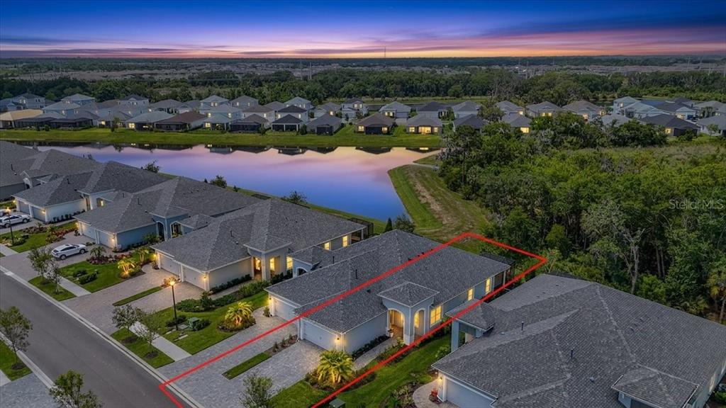 An aerial view shows a suburban house with a paved driveway and a backyard pond — 11675 GREAT BROOK LANE, PARRISH, FL
