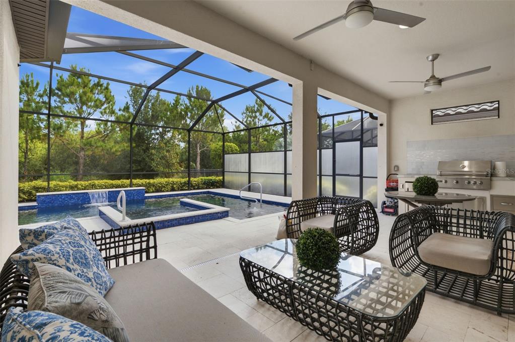 A covered patio features outdoor furniture, a built-in grill, and a screened-in pool area — 9750 HIGHLAND PARK PLACE, PALMETTO, FL
