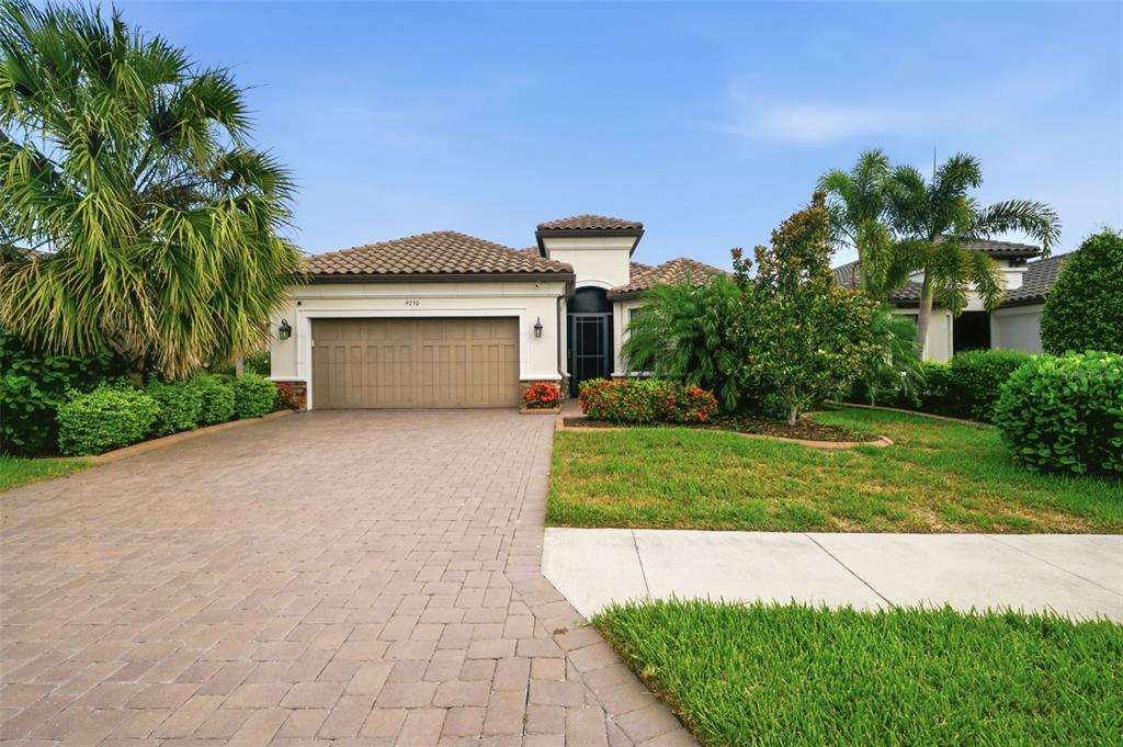 A single-story house with a paved driveway, a two-car garage, and landscaped front yard — 9750 HIGHLAND PARK PLACE, PALMETTO, FL