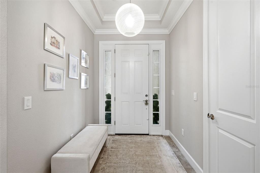 A bright entryway features a white front door, a bench, and a modern pendant light — 9750 HIGHLAND PARK PLACE, PALMETTO, FL