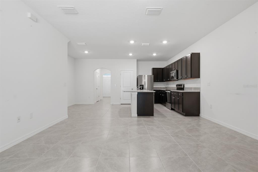 A kitchen with dark cabinets, stainless steel appliances, and a central island on tile flooring — 13753 NW 9TH ROAD, NEWBERRY, FL